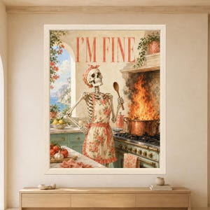 Framed I'm Fine skeleton kitchen wall art showing a skeleton in a floral apron beside a large copper pot engulfed in flames inside a sunny retro Mediterranean-style kitchen.
