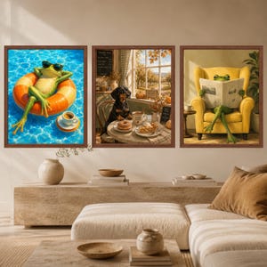 May include: A set of three framed wall art prints. The left print shows a frog in sunglasses on an orange pool float. The centre print features a dachshund at a table with a donut. The right print depicts a frog reading a newspaper in a yellow chair.