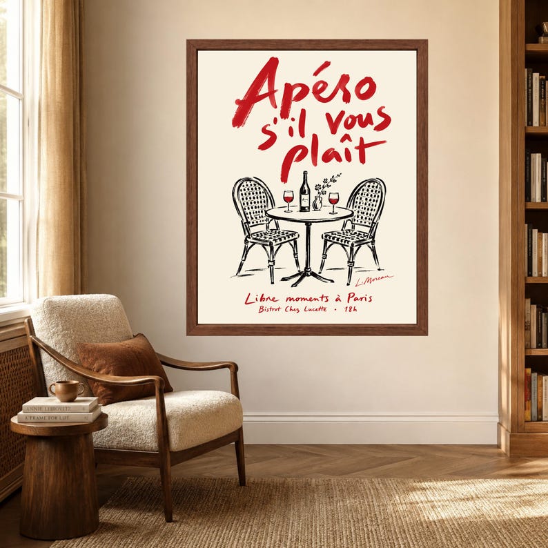 May include: A framed wall art print featuring a black and white line drawing of a bistro table and two chairs. The text reads Ap&eacute;ro s'il vous pla&icirc;t, Libre moments &agrave; Paris, Bistrot Chez Lucette, 18h in red and black ink on a cream background.