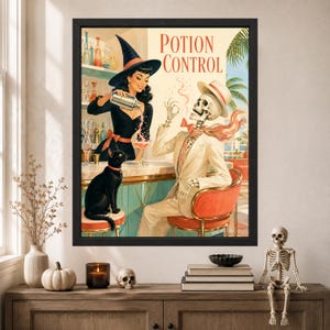 Op de afbeelding: Een ingelijste kunstdruk getiteld Potion Control met een vintage-stijl illustratie van een persoon met een heksenhoed die een drankje inschenkt voor een skelet in een pak, met een zwarte kat op een kruk in een bar met palmbomen.