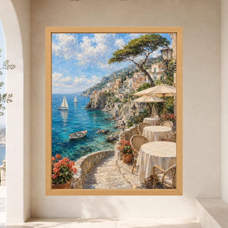 Pu&ograve; includere: Un dipinto paesaggistico incorniciato che raffigura un villaggio costiero mediterraneo con edifici in pietra su una scogliera, un mare turchese con barche a vela e una terrazza in primo piano con tavoli rotondi e sedie in vimini.