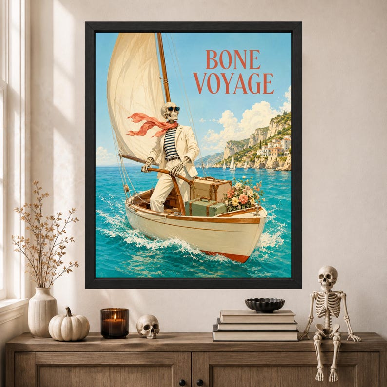 May include: A framed wall art print titled BONE VOYAGE featuring a skeleton wearing sunglasses, a white blazer, and a striped shirt, steering a sailboat on blue water. The boat carries vintage luggage and flowers near a coastal cliffside.