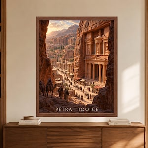 Framed Petra 100 CE wall art showing a reconstructed Nabataean city with the Treasury carved into rose sandstone cliffs, crowded streets, camel caravans, market stalls and desert mountains in warm evening light.