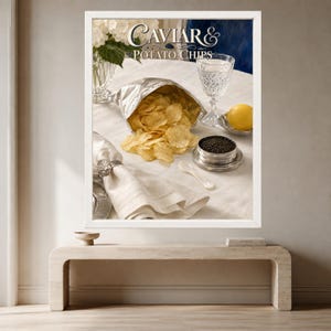 May include: A framed print titled Caviar & Potato Chips featuring a silver foil bag of ruffled potato chips, a crystal glass, a yellow lemon, a small tin of black caviar with a white spoon, and a white napkin with a shell napkin ring.