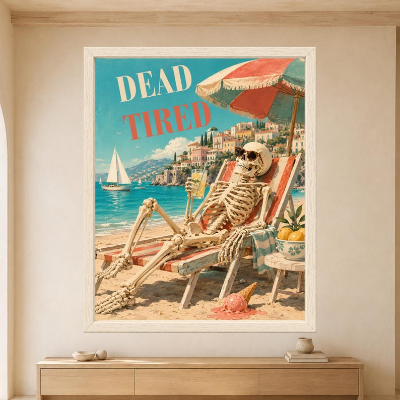 Framed Dead Tired skeleton wall art featuring a sunglasses-wearing skeleton relaxing on a striped beach chair with a drink beside a turquoise Mediterranean sea, sailboats and colorful coastal town.