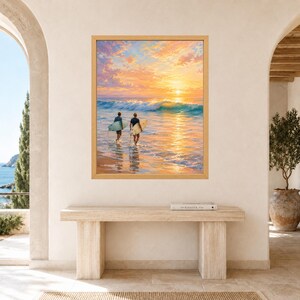 May include: A framed wall art print depicting two individuals carrying surfboards into the ocean at sunset. The scene features a vibrant orange and yellow sky reflecting on the water, with a breaking wave and a sandy beach in the foreground.
