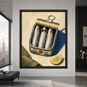 Framed sardine tin wall art showing three silver sardines inside an open can, with the middle fish wearing red sunglasses beside a lemon wedge on a cream, blue and olive background.