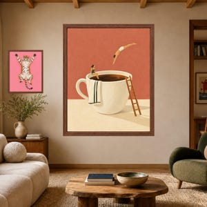 May include: A framed wall art print featuring a large white coffee cup filled with dark liquid, a person sitting on the rim, another person diving into the liquid, a towel draped over the side, and a wooden ladder leaning against the cup.