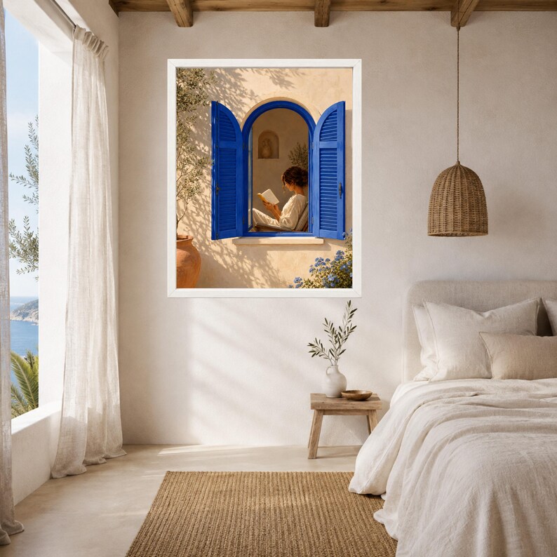 May include: A framed wall art print depicting an arched window with vibrant blue shutters set into a beige stucco wall. Through the open window, a person in light clothing sits and reads a book. The scene includes soft shadows and foliage.