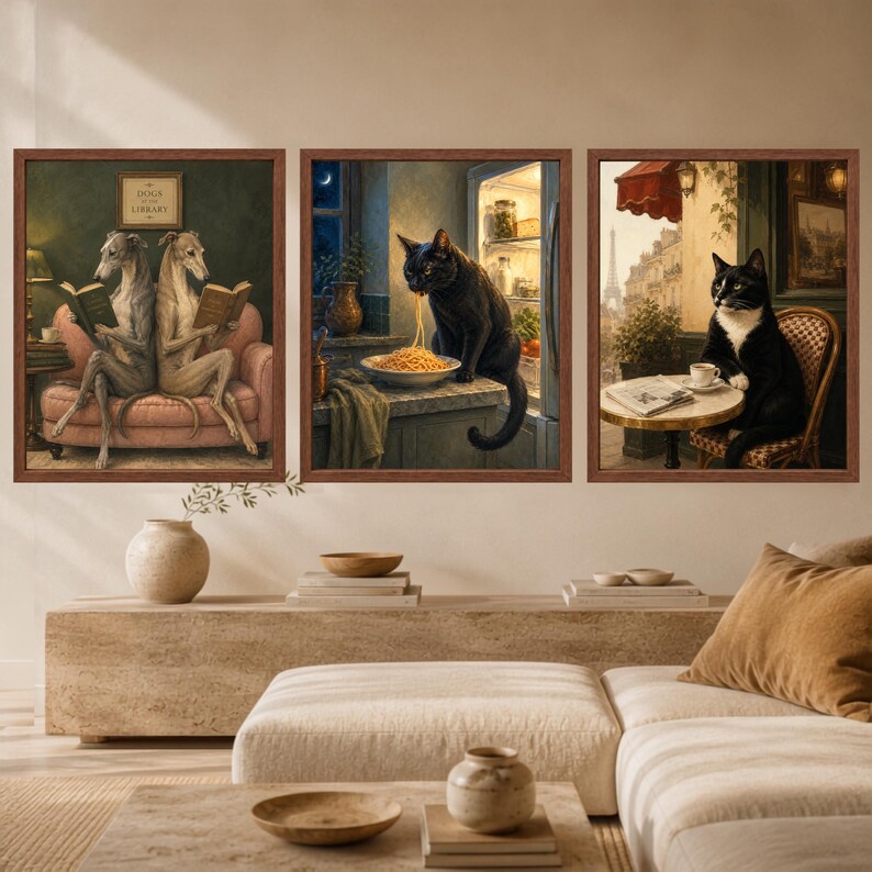 May include: Three framed wall art prints featuring anthropomorphic animals. The left print shows two grey dogs reading books on a pink sofa. The center print depicts a black cat eating spaghetti in a kitchen. The right print shows a tuxedo cat at a cafe.