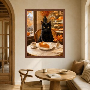 May include: A framed wall art print depicting a black cat sitting at a round marble table in a cafe. On the table sits a slice of pumpkin pie with whipped cream, a cup of coffee, and a small vase of orange autumn leaves. A window shows trees.
