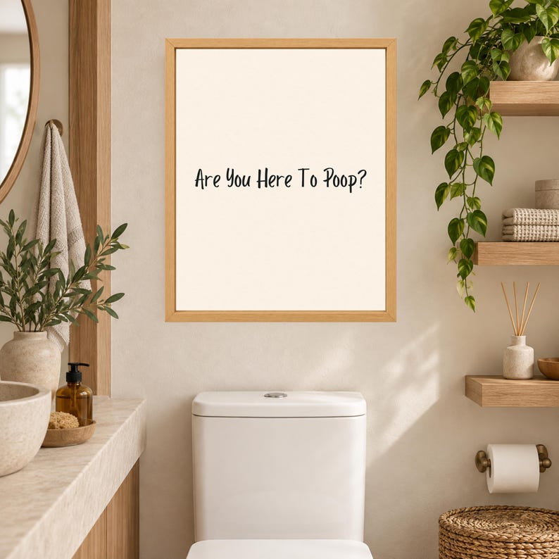 May include: A rectangular wall art piece in a light wood frame featuring a cream-colored background with the black text "Are You Here To Poop?" centered on the print. The sign is displayed on a wall above a white toilet in a bathroom setting.