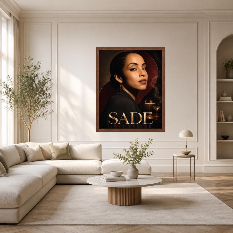K&ouml;nnte beinhalten: Ein gerahmter Wandkunstdruck mit einem Portr&auml;t von Sade und dem Text SADE LOVE DELUXE in goldener Schrift. Das Bild zeigt eine Person in einem schwarzen Oberteil vor einem dunklen Hintergrund mit einer leuchtenden Lampe und einem Martiniglas.