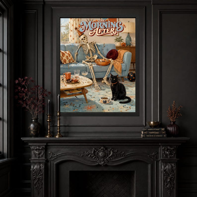 May include: A framed wall art print titled The Morning After featuring a skeleton wearing a party hat sitting on a blue sofa with a bowl of snacks, a coffee table with drinks, and a black cat sitting on a patterned rug in front of the sofa.