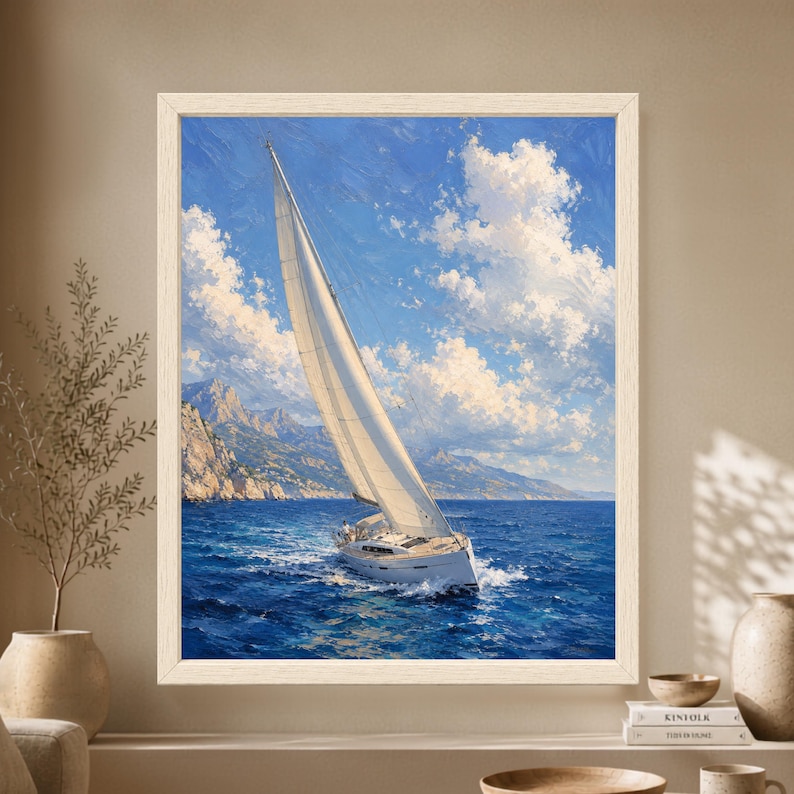 Framed sailboat wall art showing a white sailing yacht leaning into the wind on a deep blue ocean with a rocky mountain coastline and large white clouds under a bright blue sky.