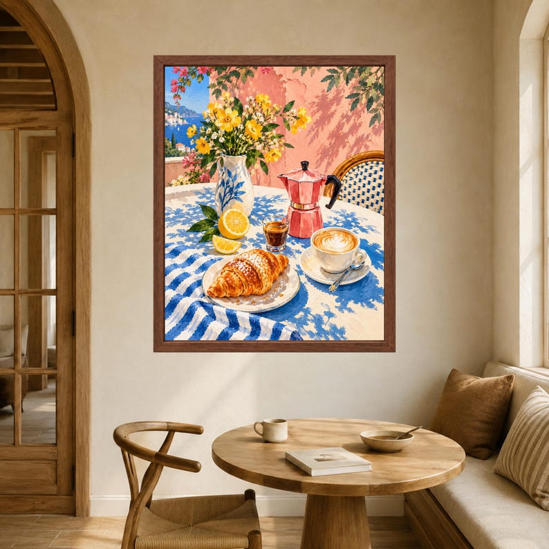 May include: A framed wall art print depicting a sunny outdoor scene with a croissant on a plate, a cup of latte, a red moka pot, a small glass of espresso, a lemon, and a vase of yellow flowers on a blue and white striped tablecloth.