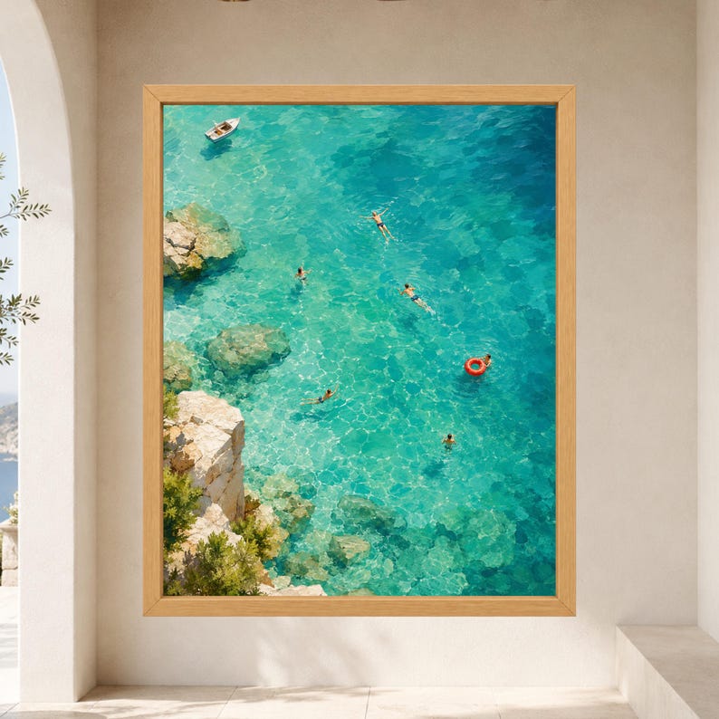 Puede incluir: Una impresi&oacute;n de arte mural enmarcada que muestra una vista a&eacute;rea de agua de mar turquesa con acantilados rocosos a la izquierda. Varias personas nadan en el mar claro y una persona flota con un anillo de nataci&oacute;n circular naranja.