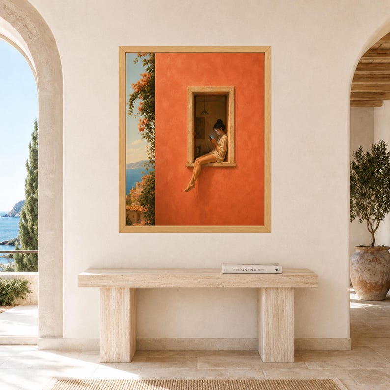 K&ouml;nnte beinhalten: Ein gerahmter Wandkunstdruck mit einer leuchtend orangefarbenen Geb&auml;udefassade, in deren Fensterrahmen eine Person sitzt und auf ein Mobilger&auml;t schaut. Die Szene zeigt einen K&uuml;stenblick mit blauem Wasser, fernen H&uuml;geln und gr&uuml;nem Blattwerk.