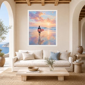May include: A framed wall art print featuring a person walking on a sandy beach at sunset while carrying a pink surfboard. The scene captures the ocean waves, a reflection on the wet sand, and a sky filled with soft orange and blue clouds.