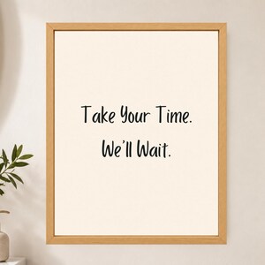 May include: A rectangular wall art piece featuring a light beige background enclosed in a light-toned wooden frame. The text Take Your Time. We'll Wait. is printed in a simple black sans-serif font in the center of the print.