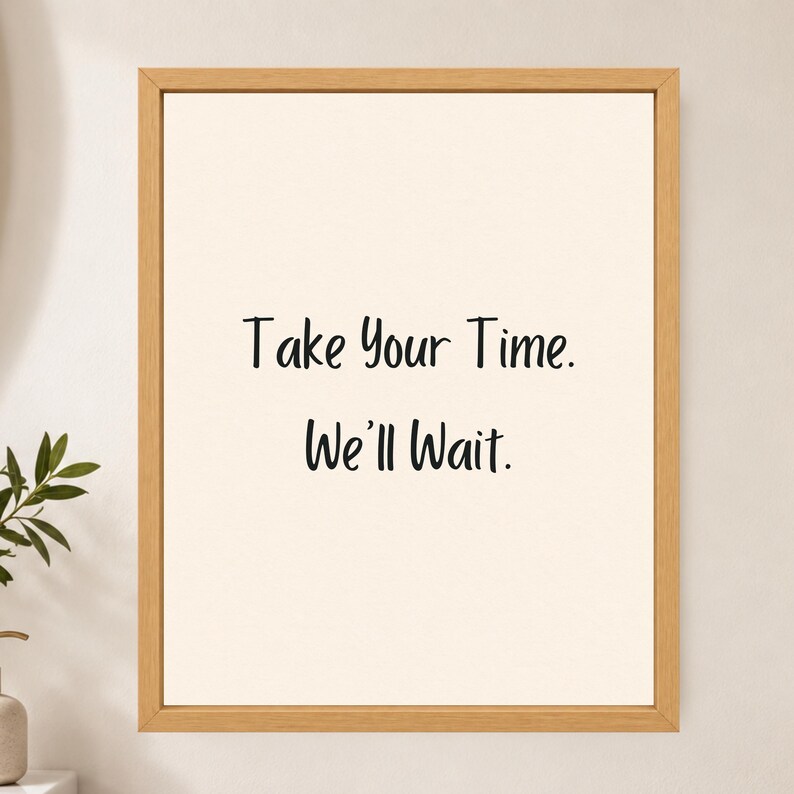 May include: A rectangular wall art piece featuring a light beige background enclosed in a light-toned wooden frame. The text Take Your Time. We'll Wait. is printed in a simple black sans-serif font in the center of the print.