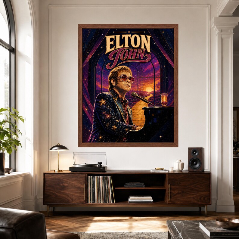 May include: A framed wall art print featuring a stylized illustration of Elton John playing a black piano. The artwork displays a starry night sky, a yellow brick road leading to a sunset, and the text ELTON JOHN in bold, decorative lettering.