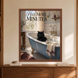Framed Five More Minutes bathroom wall art showing a wet black cat sitting in a vintage blue clawfoot bathtub beside a small coffee cup, with brass fixtures and morning light.