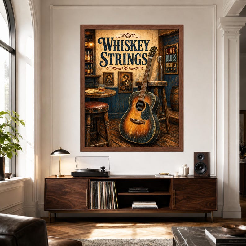 Op de afbeelding: Een ingelijste kunstdruk getiteld Whiskey Strings met een vintage akoestische gitaar die tegen een houten kruk leunt in een bar, met een glas whisky op een tafel en een bord met de tekst Live Blues Nightly.
