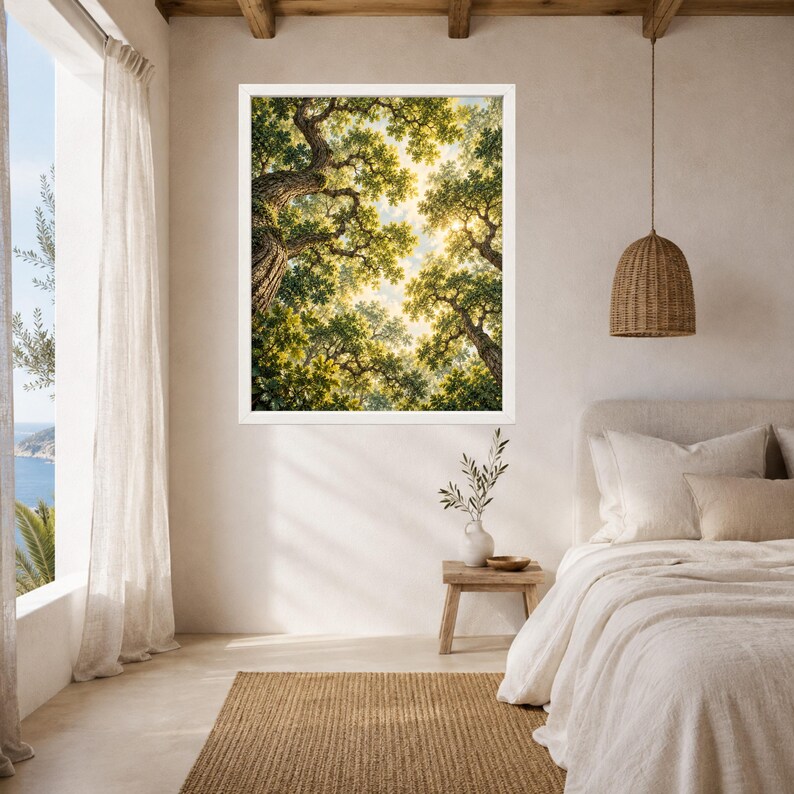 May include: A framed wall art print depicting a low-angle view of a dense forest canopy with sunlight filtering through green leaves and textured tree trunks, displayed on a plain wall above a wooden side table and a bed with white bedding.