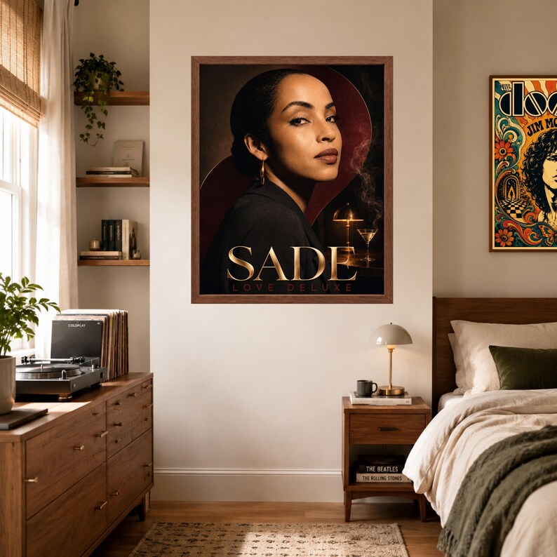 K&ouml;nnte beinhalten: Ein gerahmter Wandkunstdruck mit einem Portr&auml;t von Sade und dem Text SADE LOVE DELUXE. Das Bild zeigt eine Person in einem dunklen Blazer vor einem dunklen Hintergrund, wobei eine kleine Lampe und ein Martiniglas unten rechts zu sehen sind.