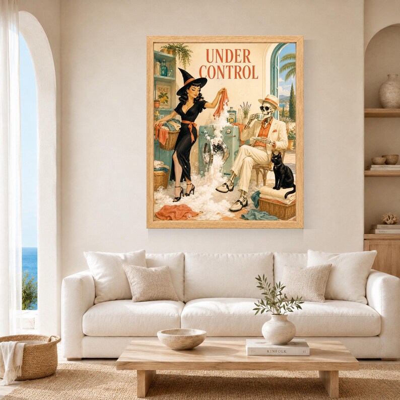 May include: A framed wall art print titled UNDER CONTROL featuring a vintage-style illustration of a person in a black dress and witch hat doing laundry with a skeleton in a beige suit and hat sitting nearby with a black cat and a washing machine.