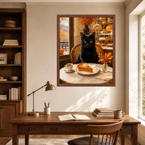 May include: A framed wall art print depicting a black cat sitting at a round marble table with a slice of pumpkin pie and a cup of coffee. The scene is set in a cafe with autumn foliage visible through a window and a display case in the background.