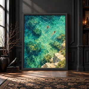 Framed aerial coastal wall art showing two swimmers in clear turquoise and emerald water above submerged rocks beside a warm limestone cove in a textured painterly style.