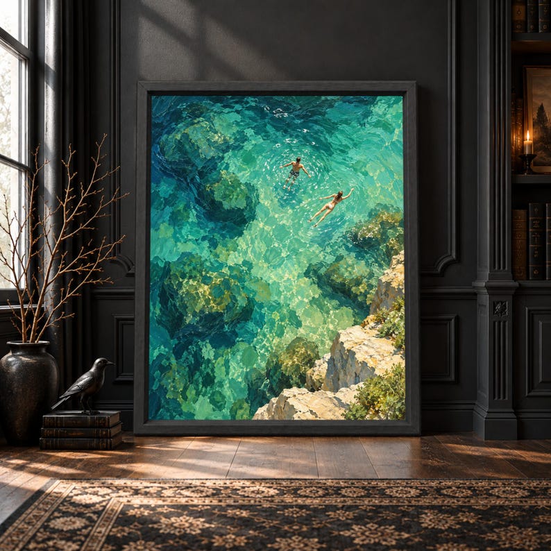 Framed aerial coastal wall art showing two swimmers in clear turquoise and emerald water above submerged rocks beside a warm limestone cove in a textured painterly style.