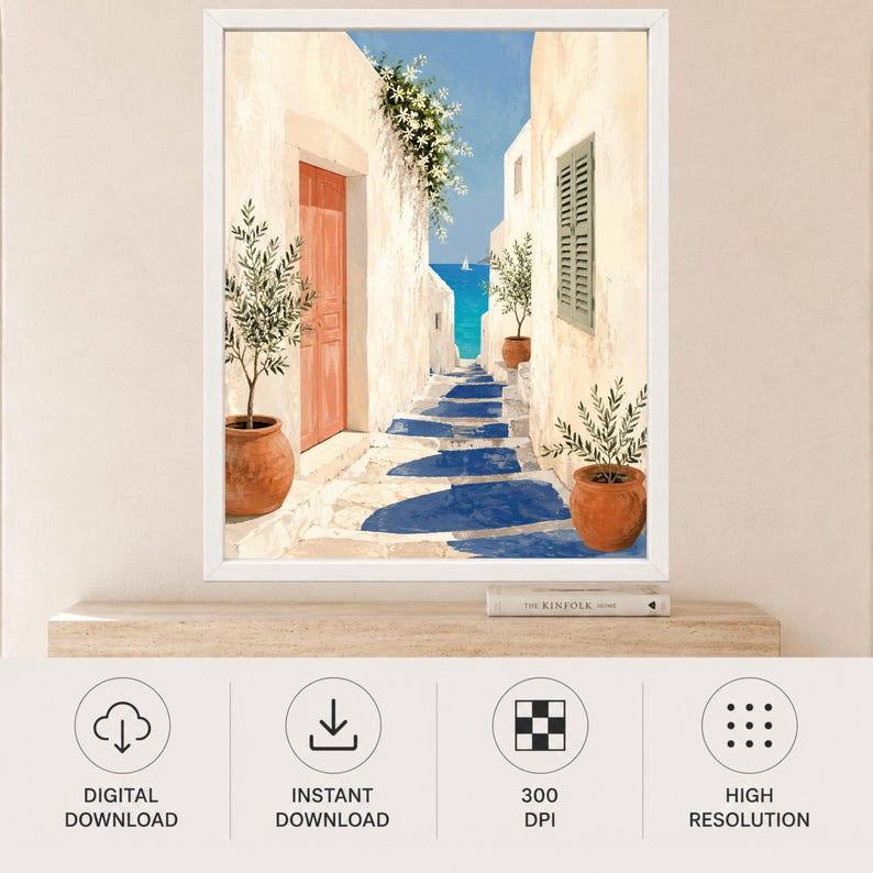 May include: A framed wall art print depicting a Mediterranean coastal scene with white stone buildings, a terracotta door, and potted olive trees. A stone pathway leads toward a bright blue sea under a clear sky, featuring deep blue shadows.