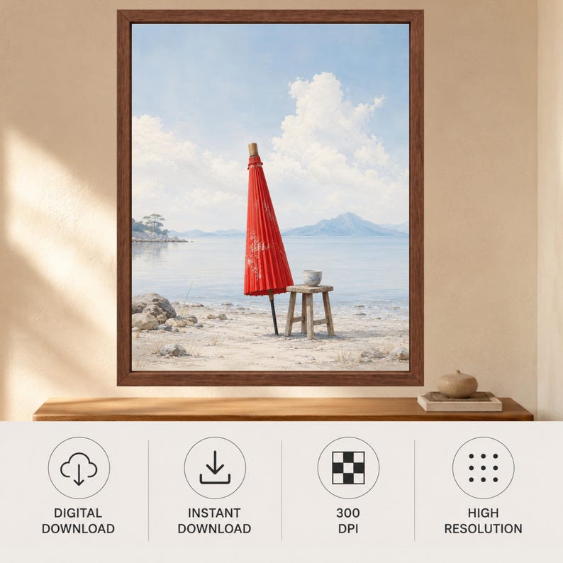 May include: A framed wall art print featuring a closed red Japanese paper umbrella standing upright on a sandy beach next to a small wooden stool, with a calm body of water, distant mountains, and a blue sky with white clouds in the background.