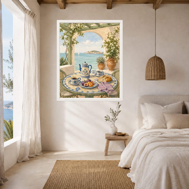 May include: A framed wall art print depicting a Mediterranean terrace scene with a round tiled table, a blue and white teapot, cups, fresh figs, and bread. The background shows a coastal view with a pergola, climbing vines, and a calm blue sea.