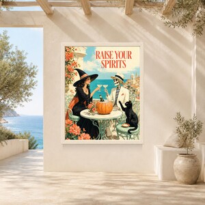 May include: A rectangular wall art print featuring a witch in a black dress and hat and a skeleton in a white suit and hat sitting at a table with a pumpkin and drinks. The text RAISE YOUR SPIRITS is printed in red at the top against a coastal background.
