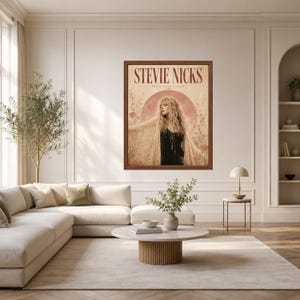 May include: A framed wall art print featuring a portrait of Stevie Nicks with long blonde hair, wearing a black top and a lace shawl. The background includes a large moon, floral illustrations, and the text STEVIE NICKS in a dark red font.