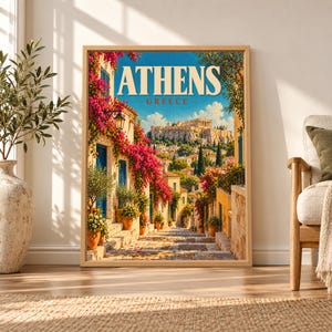 Framed Athens Greece travel poster showing the Acropolis and Parthenon above a sunlit stone street with pink bougainvillea, blue shutters, olive trees and warm Mediterranean houses.