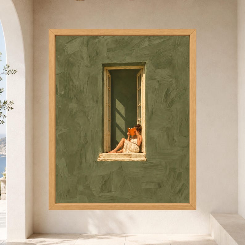 May include: A framed wall art print featuring a textured olive green wall with a central open window. A figure in a light-colored dress sits in the window frame reading an orange book, with sunlight casting distinct shadows across the scene.
