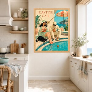 May include: A framed wall art print titled CASTING CALL featuring a vintage-style illustration of a witch in a wide-brimmed hat and a skeleton in a suit sitting by a swimming pool. A black cat sits nearby while the skeleton holds a fishing rod.