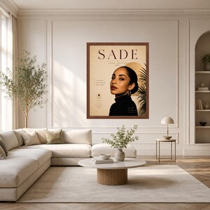 May include: A framed wall art print featuring a portrait of Sade with the text SADE LOVE DELUXE. The poster displays a beige background, a dark-haired person in a black turtleneck, a golden circular element, and a palm leaf silhouette on the right.