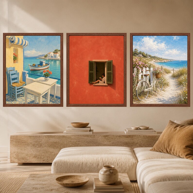 May include: A set of three framed wall art prints. The left print shows a coastal scene with a boat, table, and chairs. The centre print features a person reading in an open window on a red wall. The right print depicts a bicycle on a sandy path.