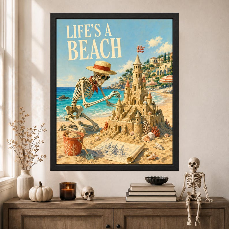 Puede incluir: Una impresi&oacute;n art&iacute;stica enmarcada que muestra un esqueleto con sombrero de paja y gafas de sol, arrodillado en una playa de arena mientras construye un castillo de arena detallado. El texto LIFE'S A BEACH est&aacute; impreso en la parte superior.
