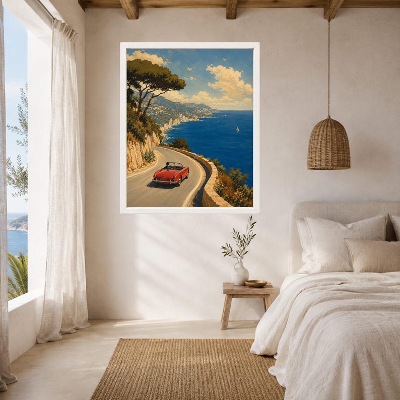 May include: A framed wall art print depicting a red convertible driving along a winding coastal road overlooking a deep blue sea. The scene features a rocky cliffside with green trees, a clear sky with light clouds, and a distant sailboat.