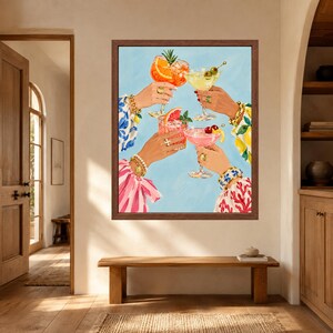 May include: A framed wall art print depicting four hands raised in a toast, each holding a different cocktail glass. The drinks include an orange spritz, a yellow martini with olives, a pink grapefruit drink, and a pink cocktail with cherries.