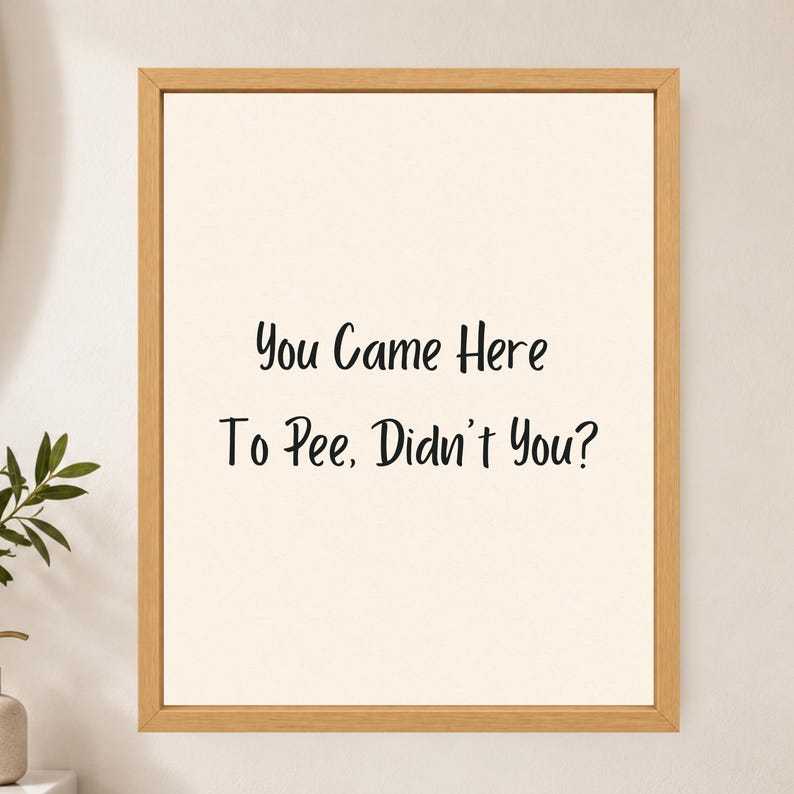 May include: A framed wall art piece featuring a light cream background with the black text "You Came Here To Pee, Didn't You?" centered in a simple, clean font. The artwork is enclosed in a light-toned wooden frame with a smooth, natural finish.