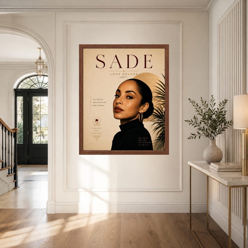 May include: A framed wall art print featuring a portrait of Sade with the text SADE LOVE DELUXE. The design includes a beige background, a golden circle, a palm leaf silhouette, and small floral icons with text accents in a dark brown wooden frame.