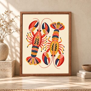 Framed colorful lobster wall art featuring two decorative red, yellow, navy and coral lobsters with dotted folk-art patterns on a warm cream background.